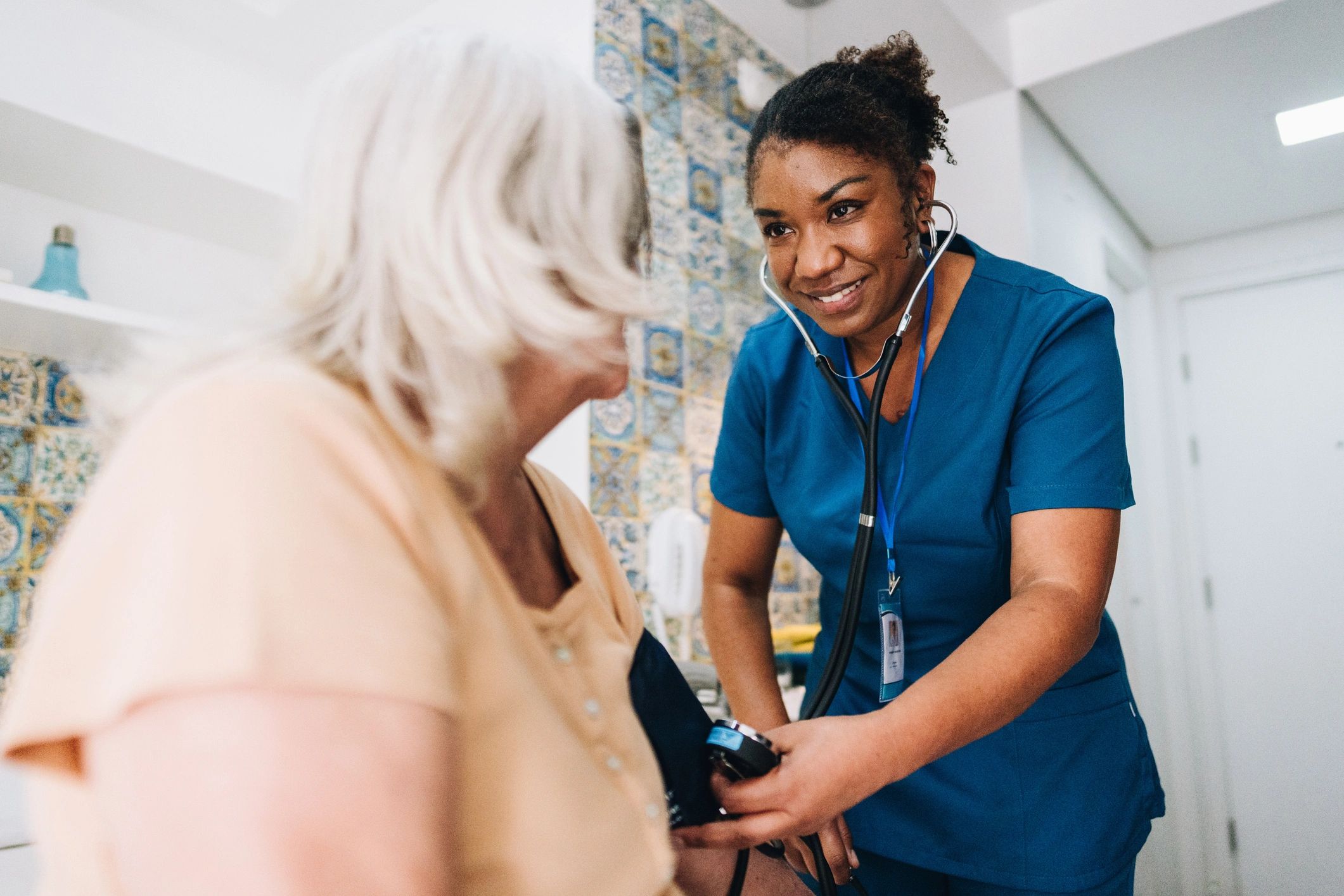 Nurse taking a senior patient's blood pressure during a home visit